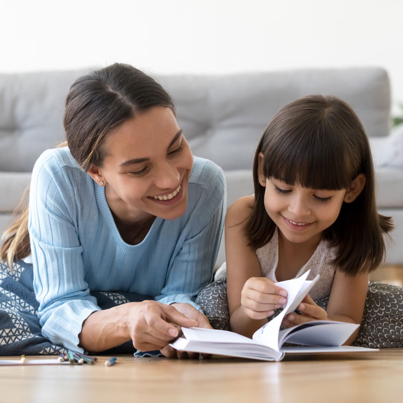mother and daughter laying on flooring reading