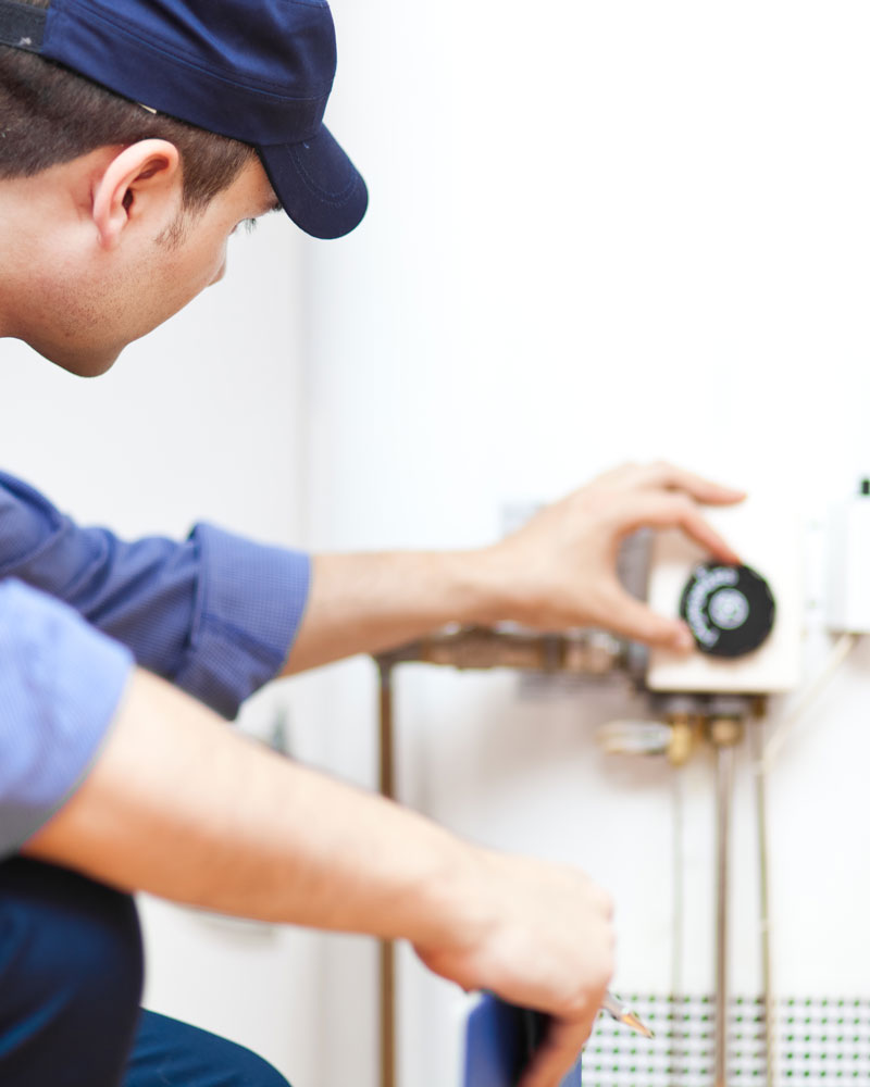 man turning dial on water heater